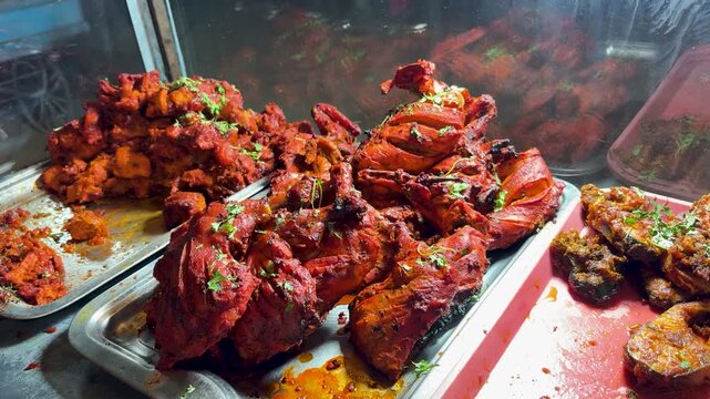 spicy tandoori chicken display in street food stall with grilled pieces and barbecue style cooking