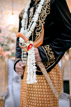 Traditional Javanese groom holding a beautiful ornate ceremonial kris dagger.