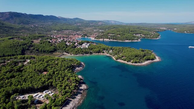 Aerial view of the charming Jelsa town nestled amidst lush greenery and the deep blue Adriatic Sea, revealing a stunning coastal landscape, Jelsa, Split-Dalmatia County, Croatia.