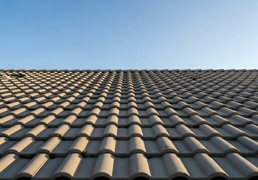 Undulating concrete tile roof under a clear blue summer sky perspective