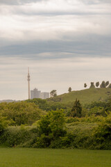 Obraz premium View of TV Tower and city skyline in Dortmund surrounded by rolling green hills and forest, soft atmospheric light and misty background.