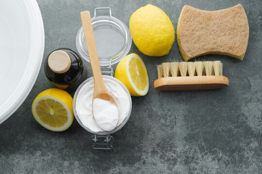 Natural remedies: baking soda, lemon, vinegar, brush, sponge, cold water for removing stains from clothes on a concrete background. Sustainable living and zero waste concept. top view