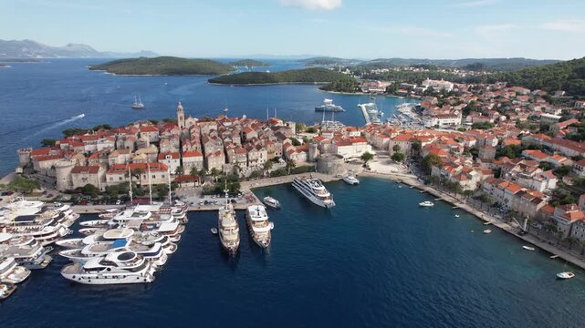 Aerial view of the old town of Korcula with its red-roofed buildings and a marina full of yachts contrasting with the deep blue sea, Korcula, Dubrovnik-Neretva County, Croatia.
