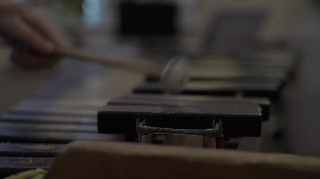 Close-up of a child's hands playing a wooden xylophone with mallets