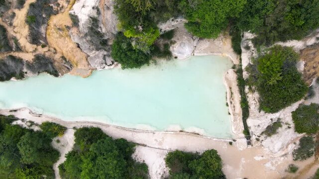 Bagno Vignoni natural pools along the city hill in Tuscany, overhead view in spring season from drone