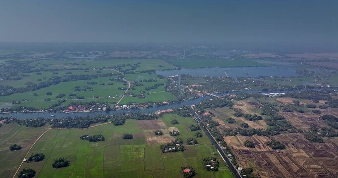 Aerial view of the Alleppey backwaters in Kerala showing traditional boats, narrow canals, palm-lined banks, village houses, and lush green paddy fields, famous tourism destination in South India.