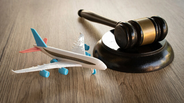 Toy airplane next to a wooden judge gavel on a wooden surface.
