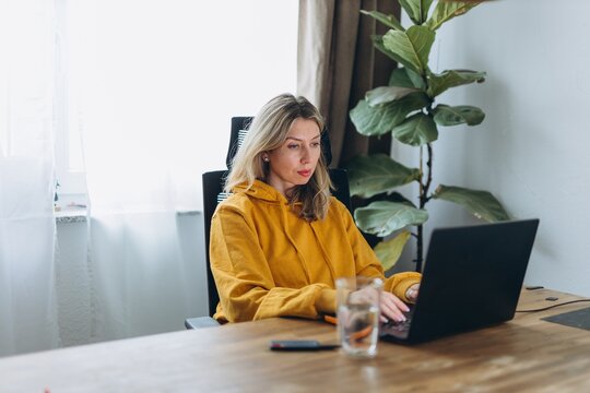 Focused woman working on laptop in home office showing deep work and productivity flow in calm remote lifestyle environment