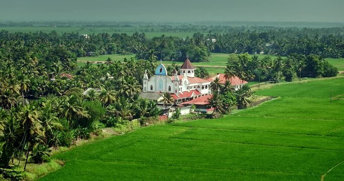 Aerial view of the Alleppey backwaters in Kerala showing traditional boats, narrow canals, palm-lined banks, village houses, and lush green paddy fields, famous tourism destination in South India.