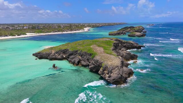 Aerial view of rocky islands and turquoise water along a white sand coastline with resorts and buildings at Watamu Beach, Kenya.