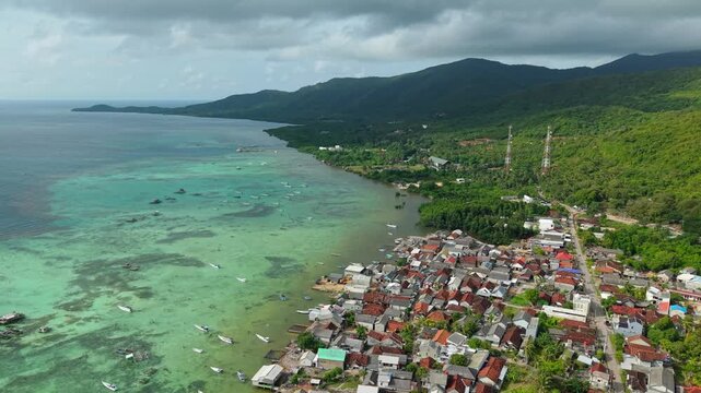 Aerial view of the vibrant Karimunjawa coastline, where the turquoise sea meets the lush green landscape of the island, Karimunjawa, Central Java, Indonesia.