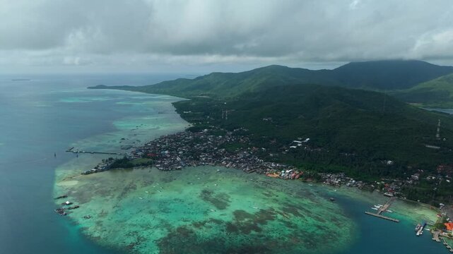 Aerial view of the town of Karimunjawa nestled between the turquoise waters and the lush green hills, captivating the eye with its vibrant contrast, Karimunjawa, Central Java, Indonesia.