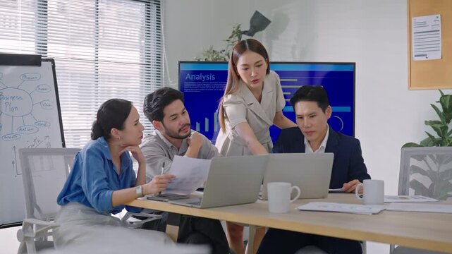 Asian business team collaborating on a digital marketing presentation. Looking at data charts for strategic planning, social media trends, and online growth success.