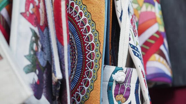 Colorful hanging tote bags with intricate mandala patterns and artistic designs in motion.