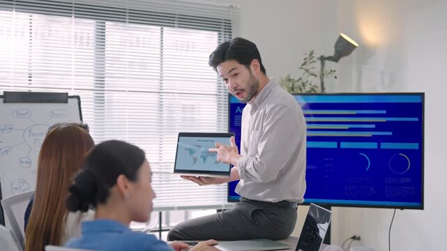 Professional Asian business people brainstorming and presenting global sales data, marketing strategy, and logistics planning in a modern office.