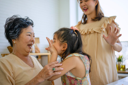 Daughter, mother and grandmother are preparing food together in the kitchen.