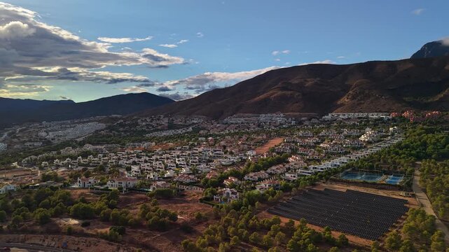Aerial view of suburban residential area near Benidorm with houses solar panels sports courts and mountain landscape