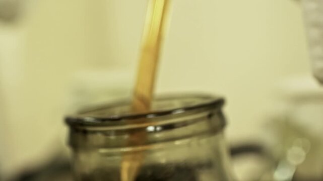 Close up of a female chemist pouring liquid chemical into laboratory glassware during a science experiment