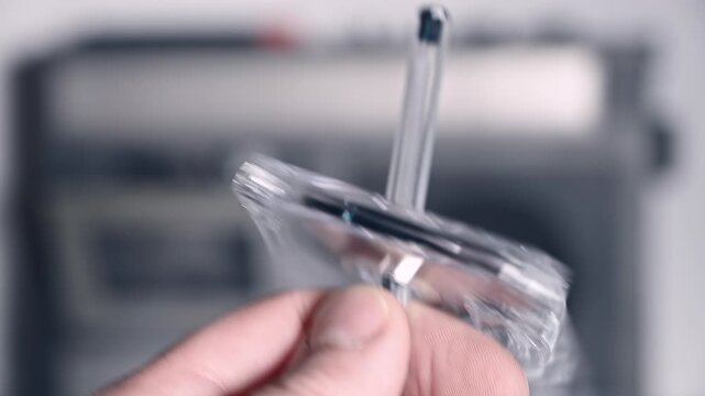 Slow motion close-up of a hand using a pen to rewind a cassette tape, with a blurred cassette radio in the background. Nostalgic scene representing analog music, retro technology 