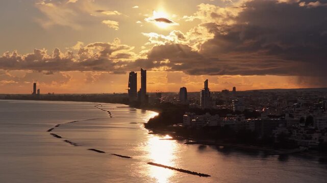 Aerial drone view of Limassol city coastline at sunset with warm golden light reflecting on the Mediterranean Sea