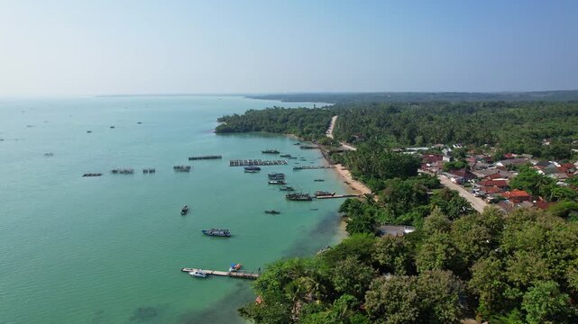 Aerial drone footage of Cipanon beach, a white sandy beach bay with small wooden fishing boats, village, in Pandeglang regency, Banten, Java island, Indonesia, nearby Tanjung Lesung tourism spot