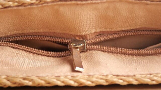 Closing and opening zipper on a textured, light brown bag detail macro shot movement.
