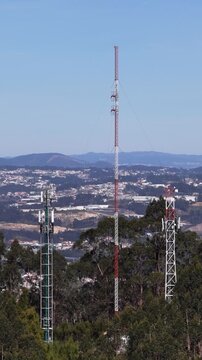 Aerial view of communication cell towers piercing the sky above a dense canopy of trees, highlighting technological advancement, Valongo, Portugal.