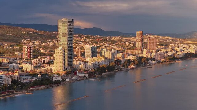 Aerial drone view of Limassol coastline showing modern architecture, residential buildings and calm Mediterranean waters under soft evening light