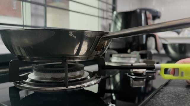 Woman lighting gas stove and lowering flame in home kitchen. Everyday cooking process, domestic lifestyle scene, preparing meal indoors.