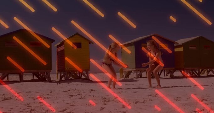 Two girls facing sparking mirroring jumps for play on sand by huts, orange streaks overlaying, ads
