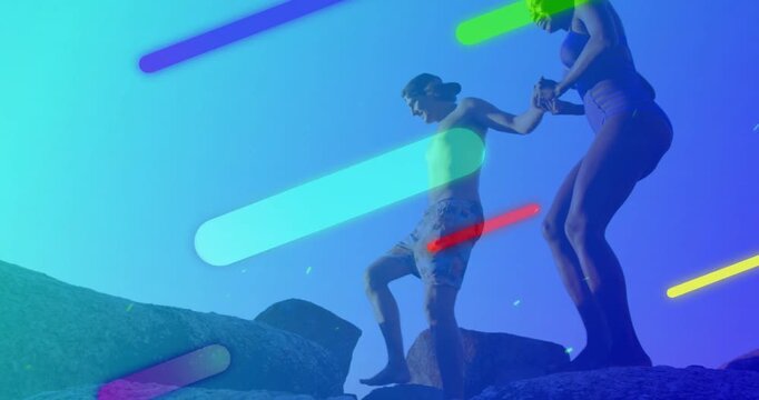 Vertical video: Man stepping, woman holding hand down rocks for safety, travel graphics streaking