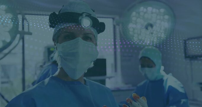 Surgical team colleagues performing surgery in OR with headlamp, gloved fingertips showing stain