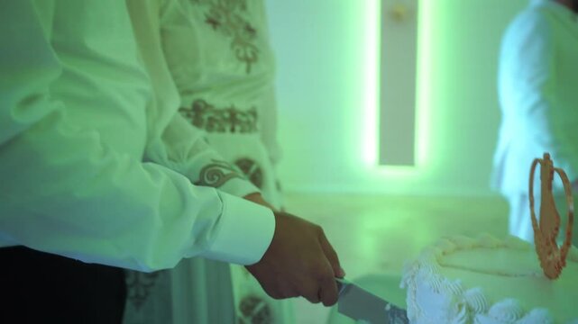 female and male hands cutting a wedding cake