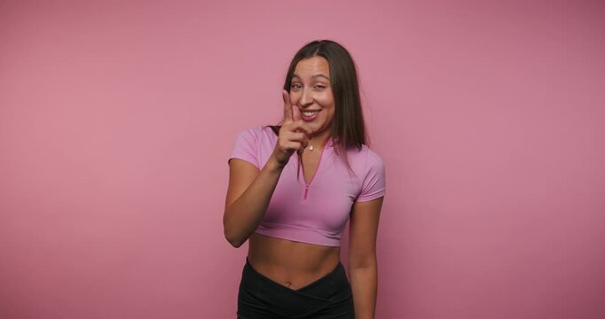 Smiling woman talks and expresses joy in fun moments in a pink background studio