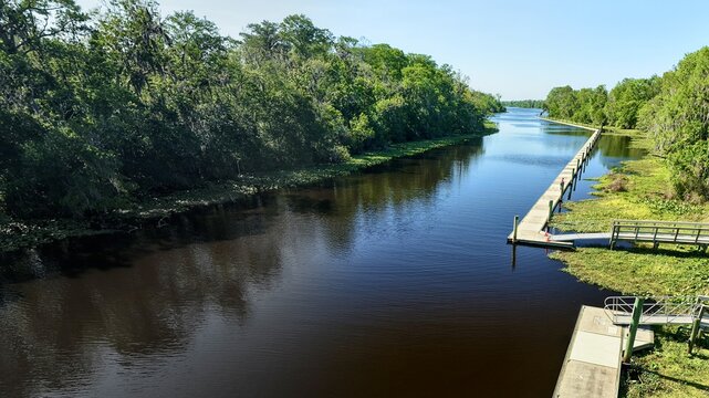 Aerial view of the dark waters reflecting the sky as they wind through lush green vegetation near Palmo Fish Camp Road, St. Augustine, Florida, United States.