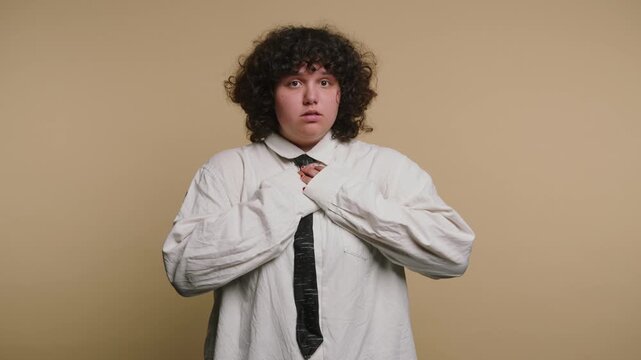 Person adjusts clothing and gestures in a simple setting with a light background