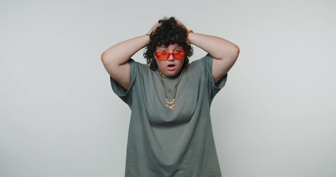 Person expresses surprise and confusion while wearing oversized glasses in a studio setting
