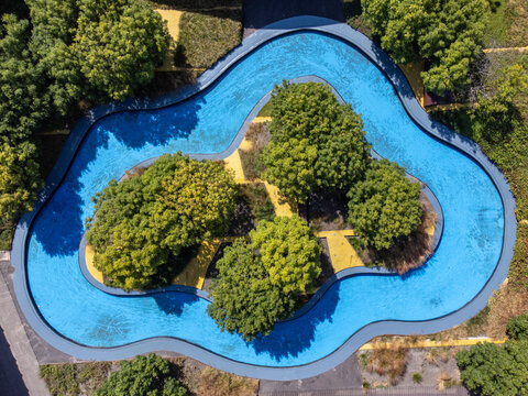 Aerial view of a unique water feature with lush greenery and yellow pathways creating a vibrant contrast, Schipperplein, Almere, Flevoland, Netherlands.