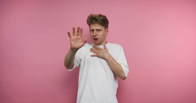 Man performs different hand gestures in front of a pink wall while expressing various feelings in a short time