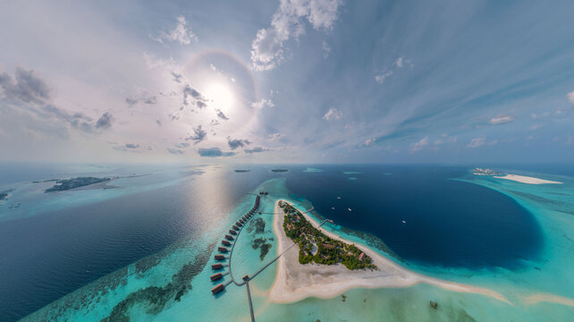Aerial view of island resorts with overwater bungalows and pristine turquoise waters under a bright sun, Male, Male, Maldives.