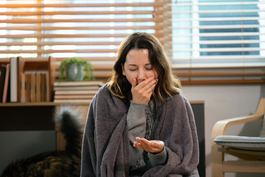 ick woman wrapped in blanket coughing and feeling unwell