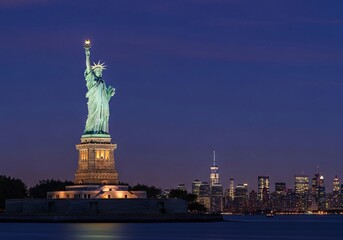 Fototapeta premium Iconic statue of liberty standing tall against a nighttime skyline backdrop
