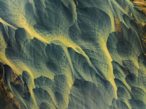 Aerial view of braided rivers carve paths through volcanic sands, a mesmerizing tapestry of grey and gold, Iceland.
