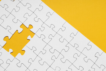 Fototapeta premium White jigsaw puzzle with missing pieces on yellow background