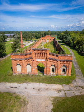 Aerial view of the striking red brick architecture of the Karosta Prison contrasts vividly against the surrounding green fields and lush trees, Liepaja, Latvia.