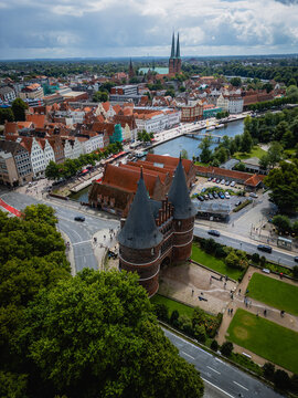 Aerial view of the iconic Holsten Gate guarding the historic city, with its red brick contrasting against the lush greenery, Lubeck, Schleswig-Holstein, Germany.