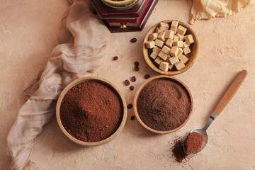 Wooden bowls with coffee powder and cubes of sugar on beige background © Pixel-Shot