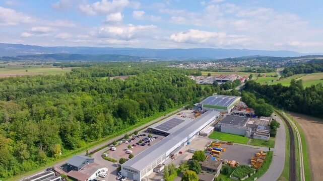 Smooth drone flight from Aarberg toward Lyss, crossing industrial zones and the Aarberg galvanizing plant in the Swiss Seeland region.