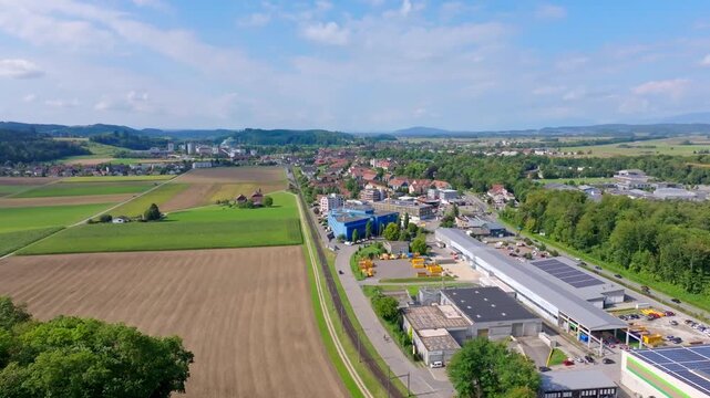 Smooth summer drone flight from the east over Aarberg&rsquo;s industrial zone towards the historic town and iconic sugar factory in Switzerland.