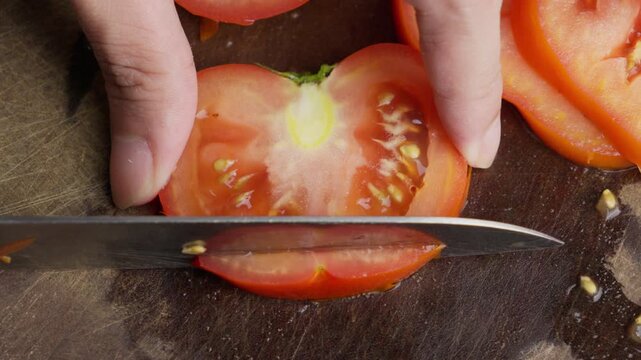 Slicing fresh tomato Solanum lycopersicum close-up, March kitchen